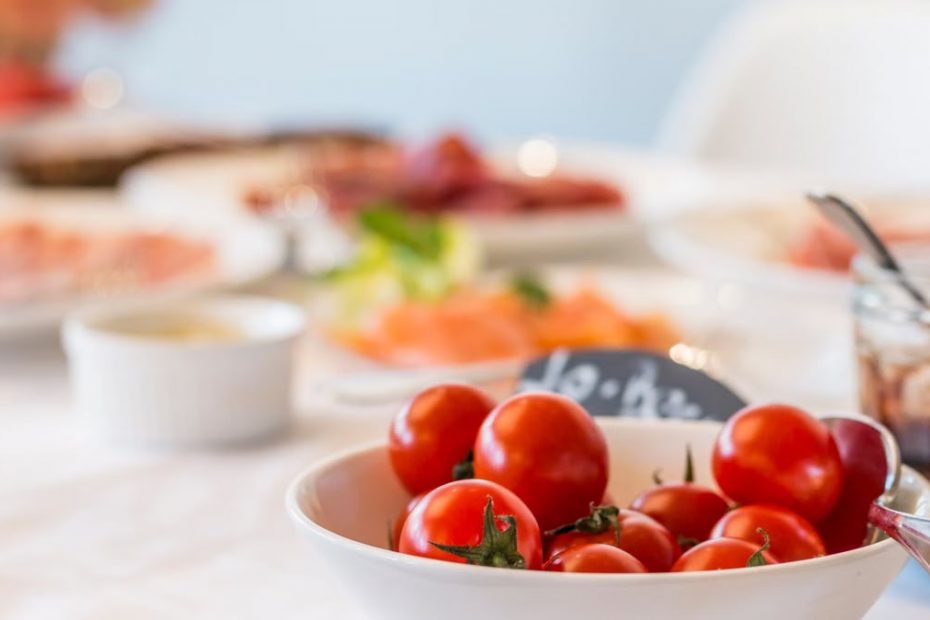 Close-up shot of vibrant cherry tomatoes in a bowl on a well-set dining table.
